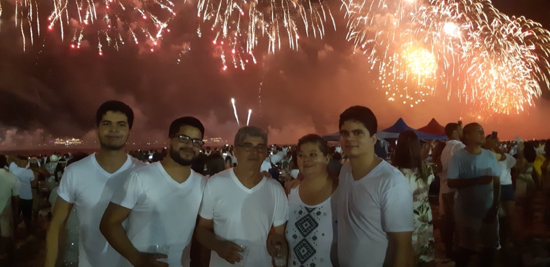 Un grupo vestido de blanco en la playa de Copacabana, con los fuegos artificiales de Año Nuevo detrás