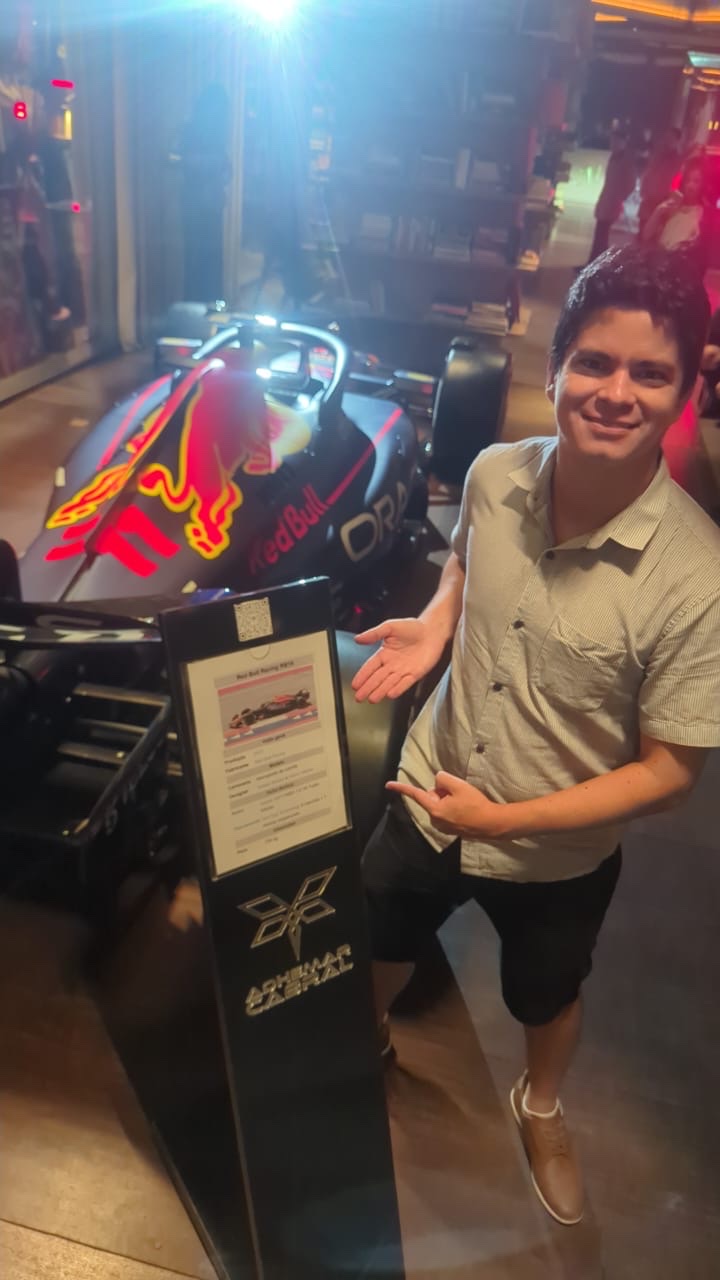 Un pasajero de JUHU Travel junto a la réplica de un monoplaza de Red Bull Racing, expuesta de noche en São Paulo