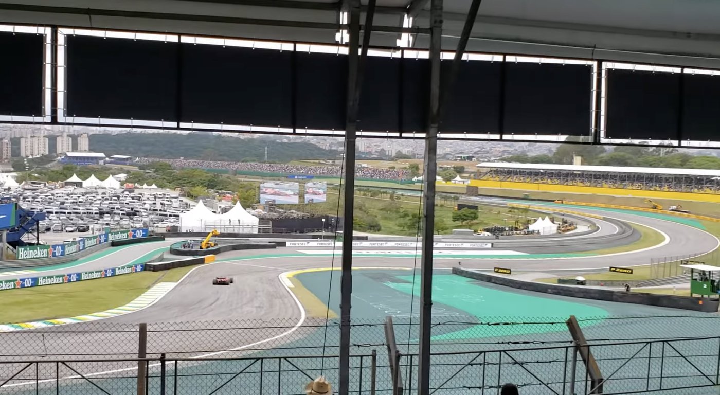 Vista desde el Sector D de Interlagos hacia la derecha: el trazado abriéndose en curva hacia la Curva do Sol, con el fondo de São Paulo