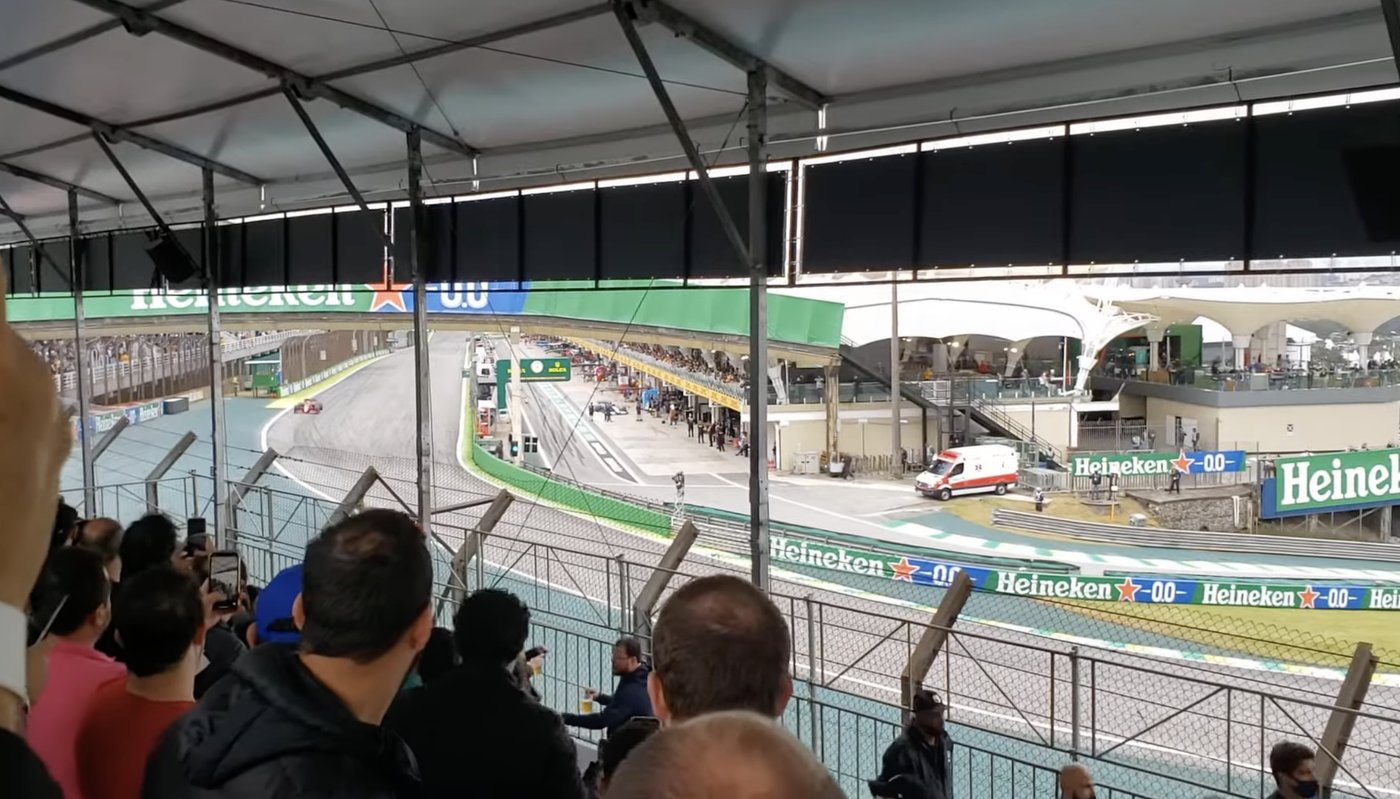 Vista desde el Sector D de Interlagos: el edificio de boxes y el movimiento del pit lane al final de la recta principal, desde una tribuna techada y llena