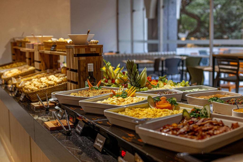 Café del hotel: mesada con panes, frutas y platos calientes, y mesas junto a los ventanales
